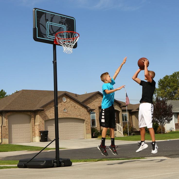 two young boys playing basketball in front of a house