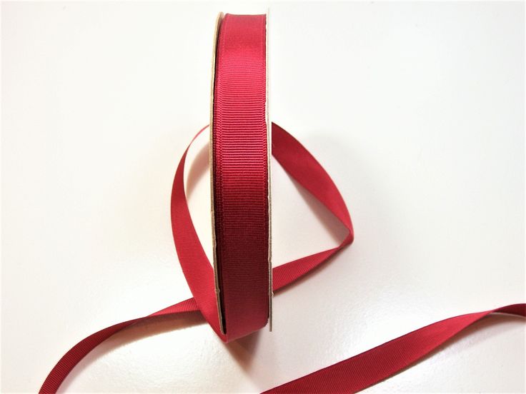 a roll of red ribbon sitting on top of a white table