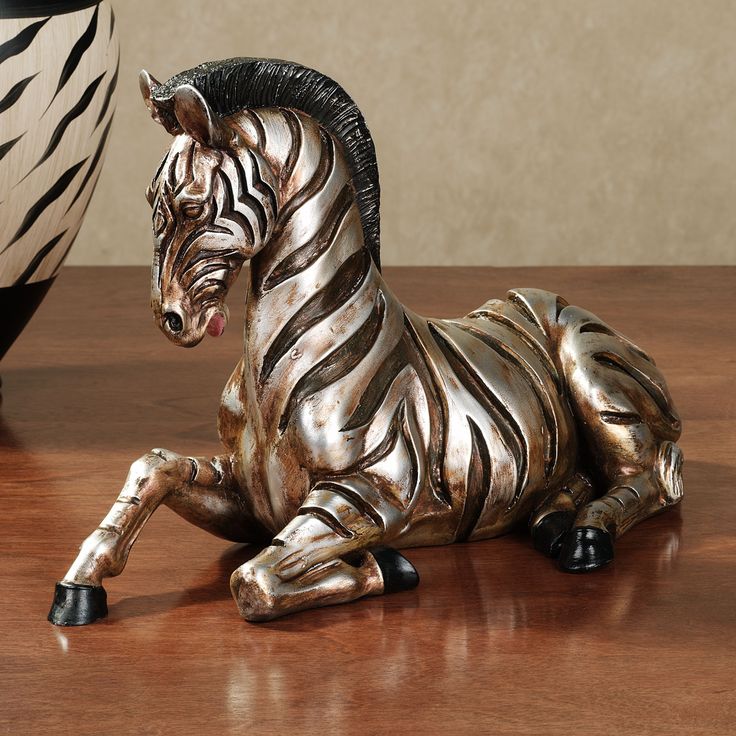 a zebra figurine sitting on top of a wooden table next to a vase