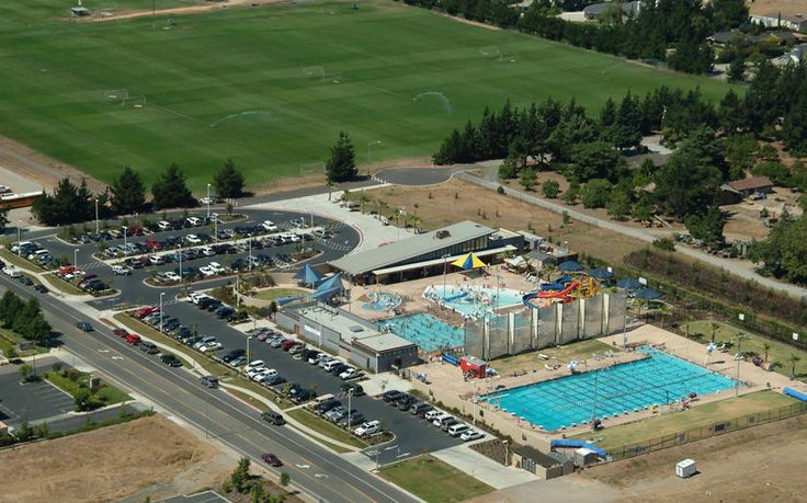 an aerial view of a large swimming pool in the middle of a parking lot with lots of cars parked around it