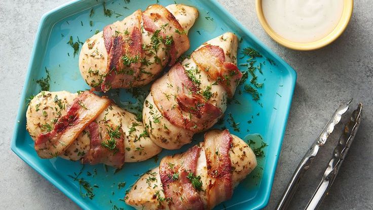 chicken wrapped in bacon and garnished with parsley on a blue platter