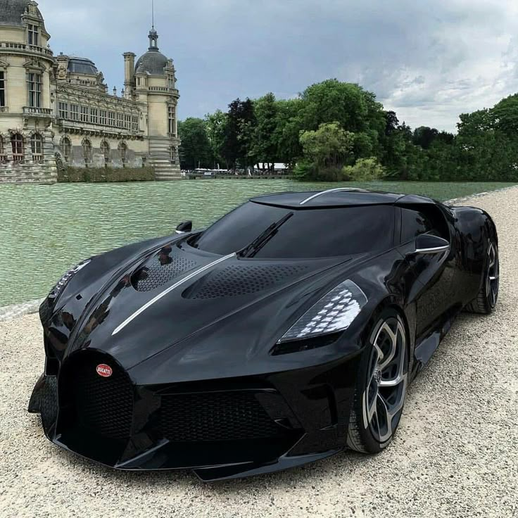 a black sports car is parked in front of a large building with a fountain behind it