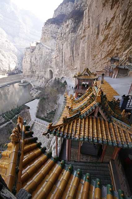 an aerial view of a building with mountains in the back ground and water running through it