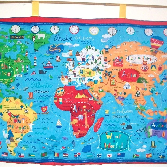 a large map of the world hanging on a wall with markers and clocks around it