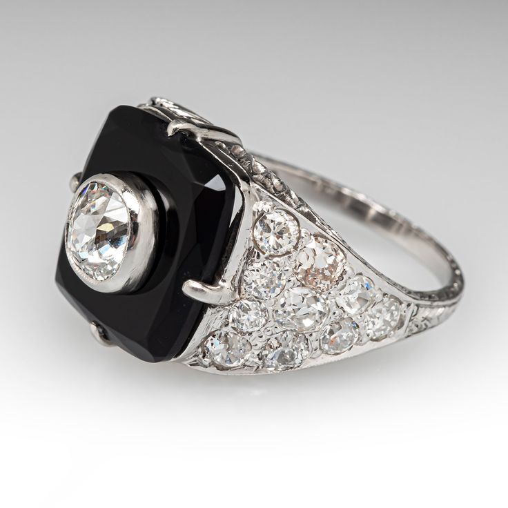 This awesome circa 1920s Art Deco dinner ring is centered with a rectangular onyx tablet in a four-prong setting. The center of the onyx is bezel set with one (1) old mine cut diamond, weighing 0.87 carats. The shoulders are each bead set with ten (10) antique cut diamonds. The ring measures 15.6mm at the top, rises 9.9mm above the finger, tapering to 1.7mm wide and 1.0mm thick at the base of the shank.  It is currently a size 7.75. Formal Art Deco Square Cut Jewelry, Art Deco Rings With Rectangular Stone For Formal Occasions, Art Deco Square Cut Diamond Jewelry, Art Deco Gemstone Signet Ring For Formal Occasions, Formal Art Deco Gemstone Signet Ring, Elegant Signet Ring With Polished Rectangular Stone, Elegant Signet Ring With Polished Finish And Rectangular Stone, Formal Art Deco Square Cut Ring, Art Deco Diamond Ring With Polished Finish