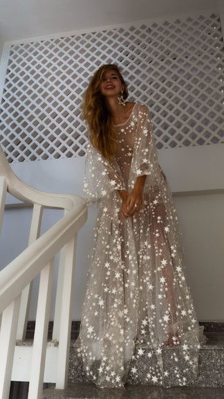 a woman is standing on the stairs in a long dress with stars all over it