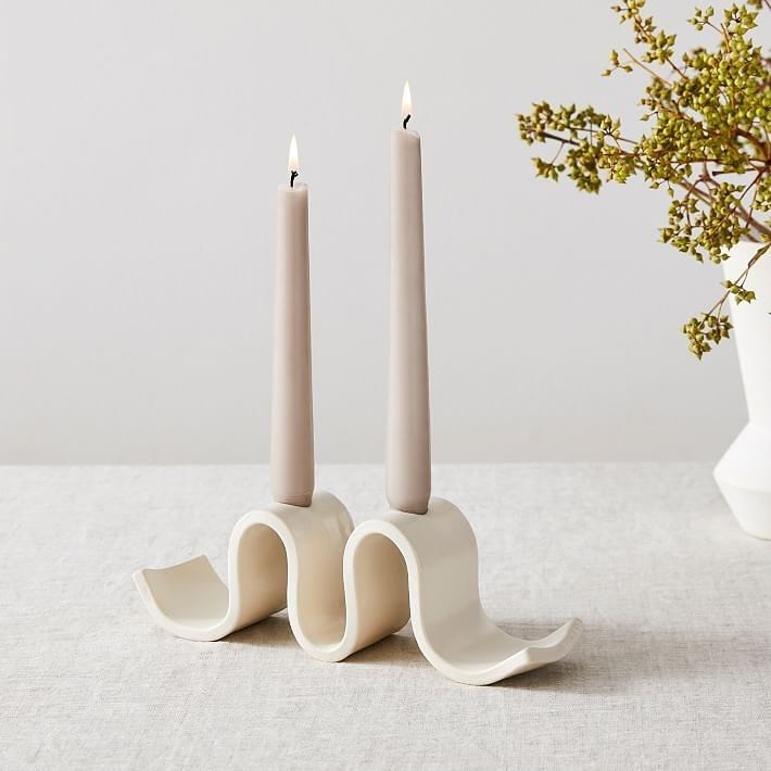 two candles sitting on top of each other in front of a vase