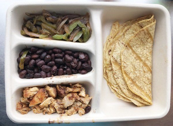 a plastic container filled with different types of food next to tortilla chips and beans