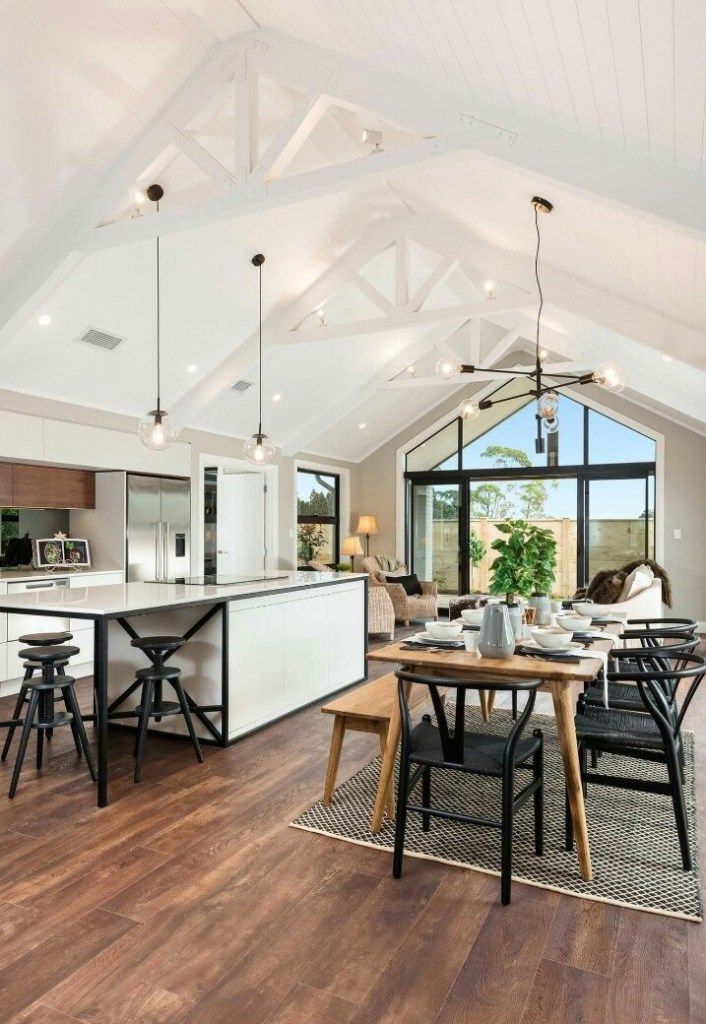 a large open concept kitchen and dining room with wood flooring, white walls and vaulted ceiling