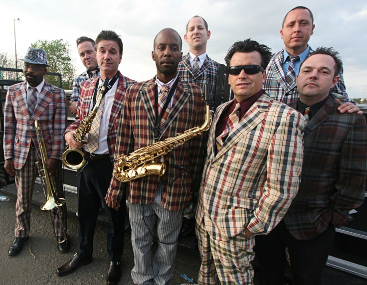 a group of men standing next to each other on top of a roof holding musical instruments