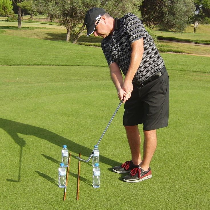 a man is playing golf with two water bottles on the tee and one has his mouth open