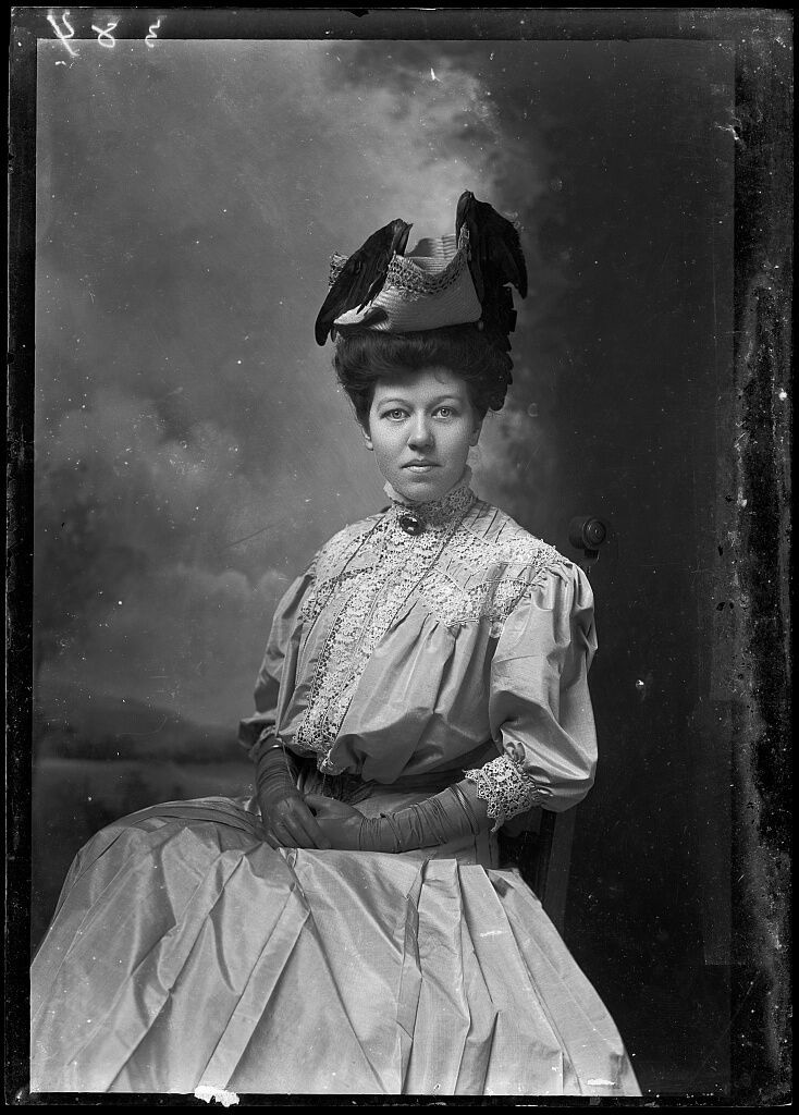 an old black and white photo of a woman holding a box with a bird on it