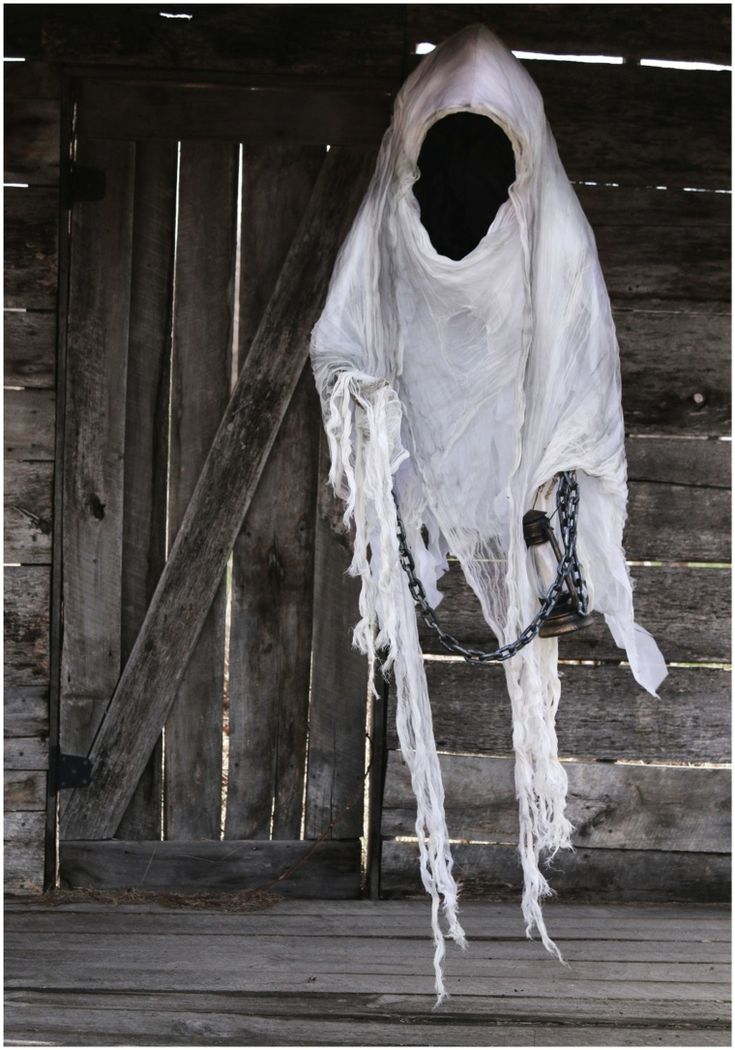 a white ghost hanging from the side of a wooden building in front of a door