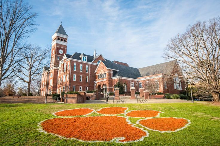 a large building with a clock tower on the top and an orange flower bed in front