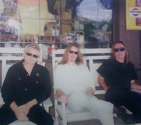 two women sitting on white chairs in front of a store window with sunglasses on their faces