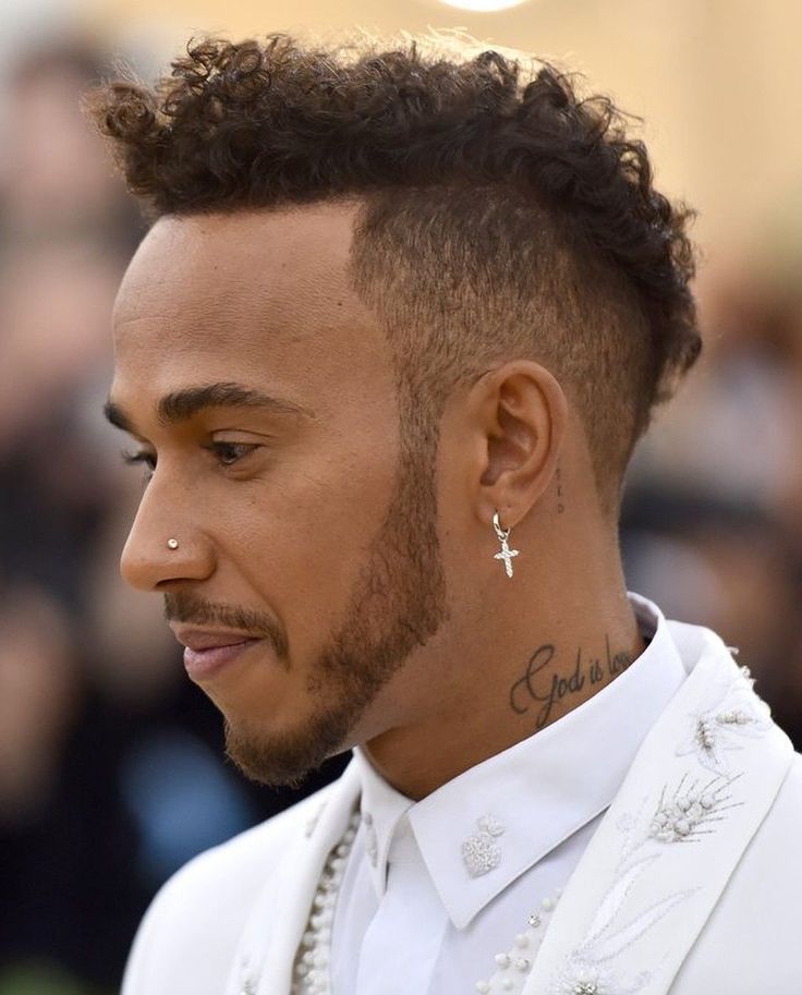 a close up of a person wearing a white suit and cross earring on his left ear