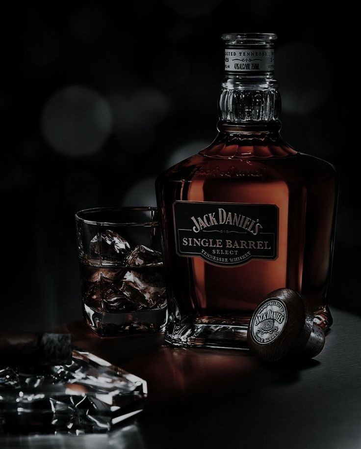 a bottle of jack daniels single barrel whiskey next to a glass with ice cubes