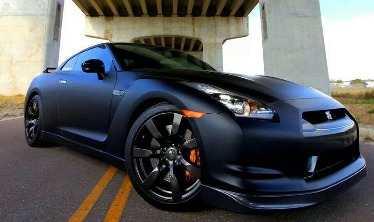 a blue sports car parked in front of a bridge