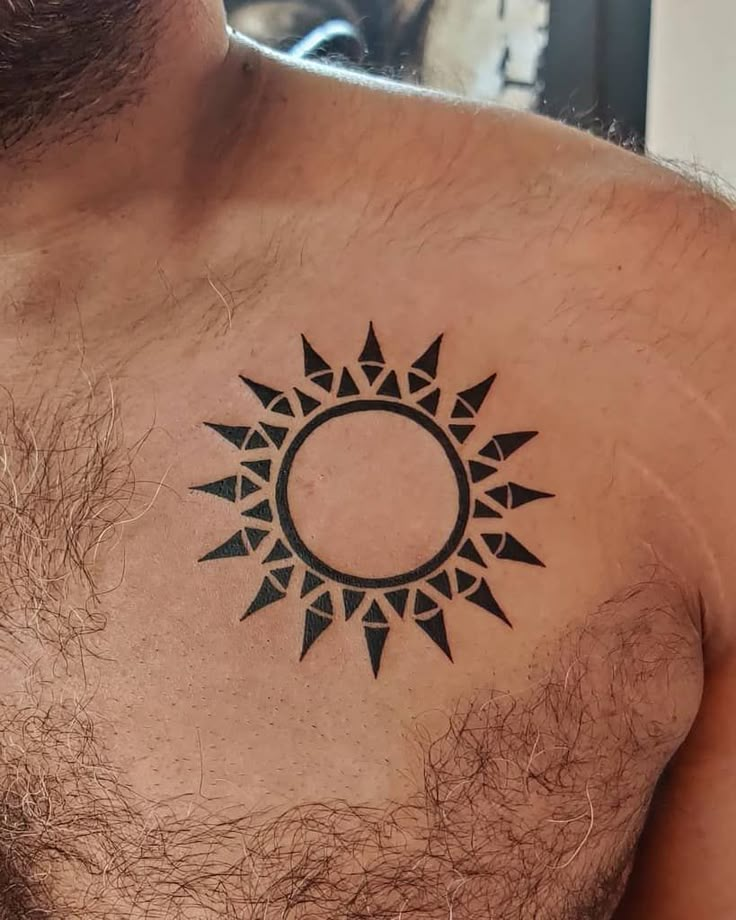 a man with a tattoo on his chest has a sun symbol in the middle of it