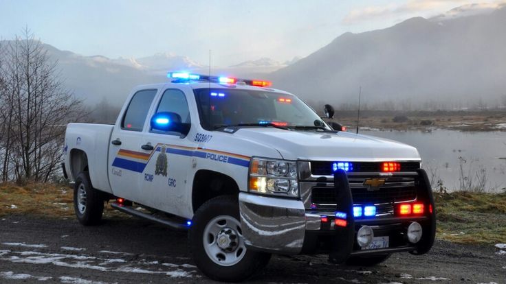 a white police truck parked on the side of a road near a body of water