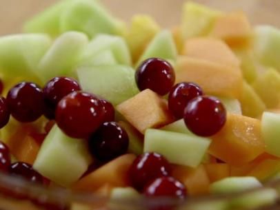 fruit salad with grapes, apples, and cranberries in a glass bowl on a table