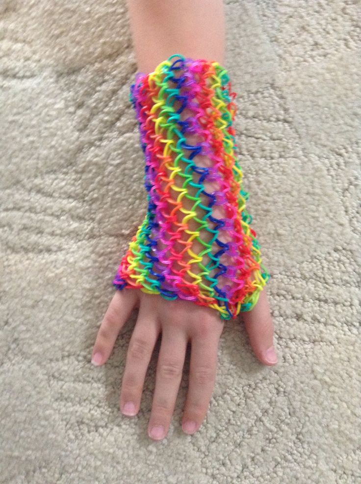 a child's hand wearing a rainbow colored wristband on top of a carpet