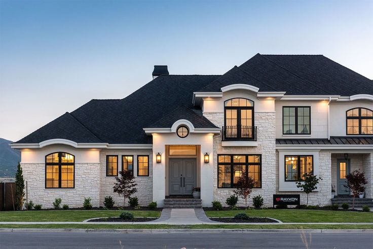 a large white house with lots of windows and lights on it's front porch