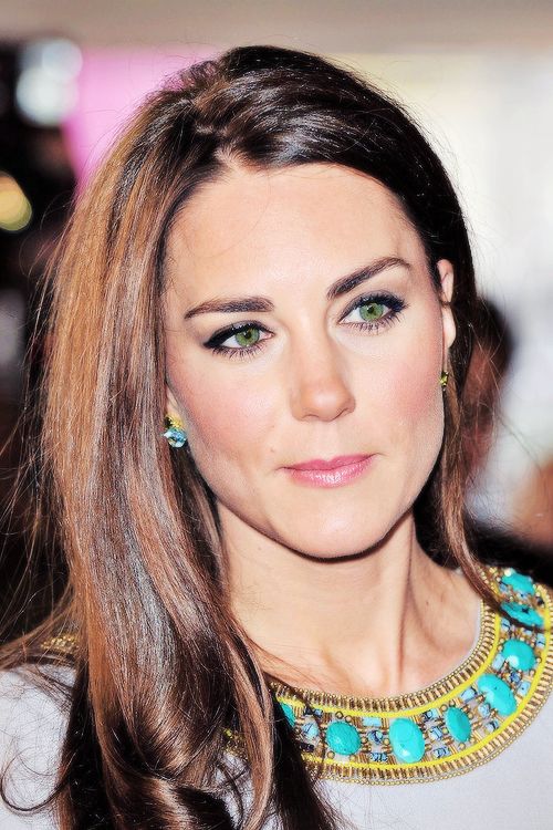 a woman with long brown hair and green eyeshadow wearing a necklace on her neck