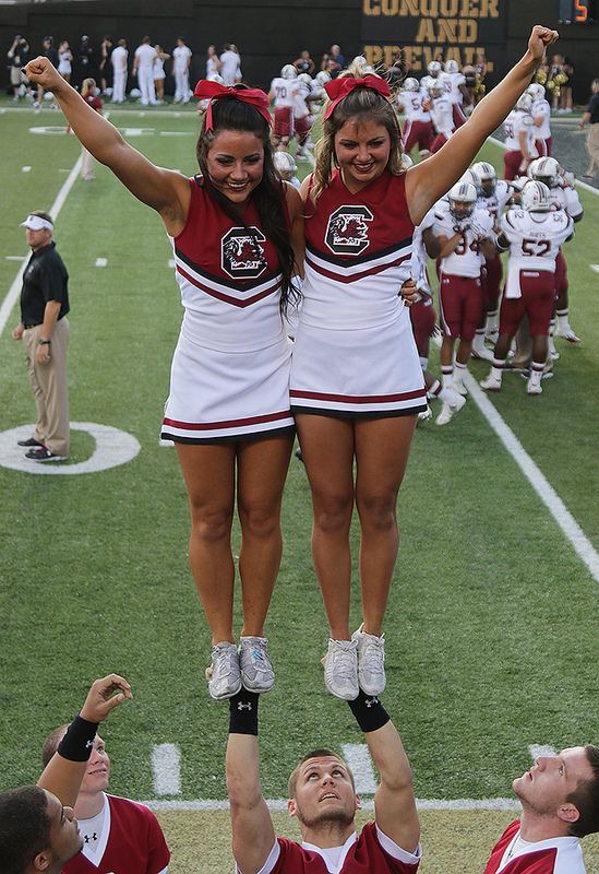 two cheerleaders are standing on the football field