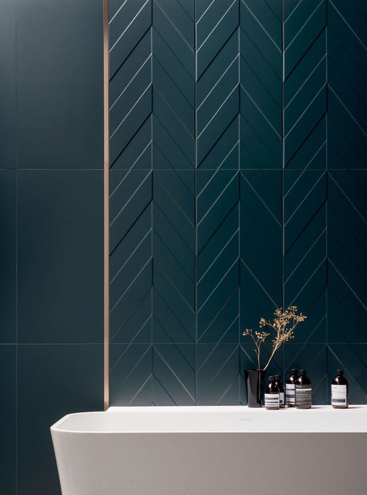 a white bath tub sitting next to a wall with a vase on it's side