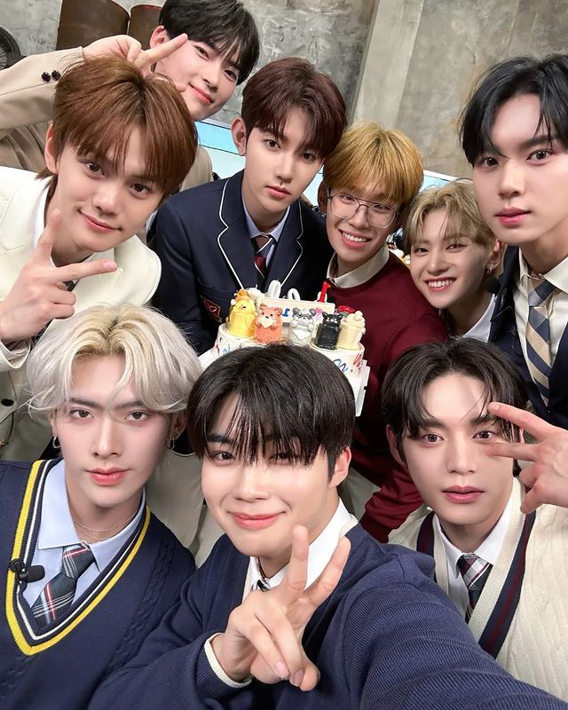 a group of young men standing next to each other in front of a birthday cake