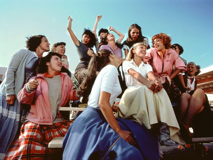 a group of people sitting on top of a bench next to each other with their arms in the air