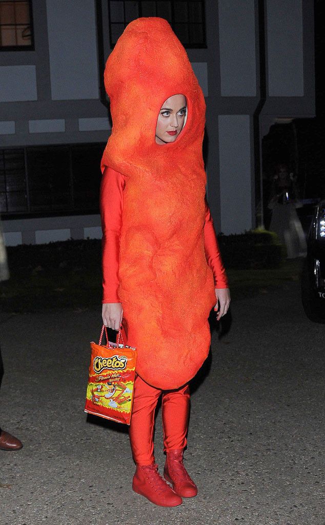 a woman in an orange costume is walking down the street with a handbag on her hip