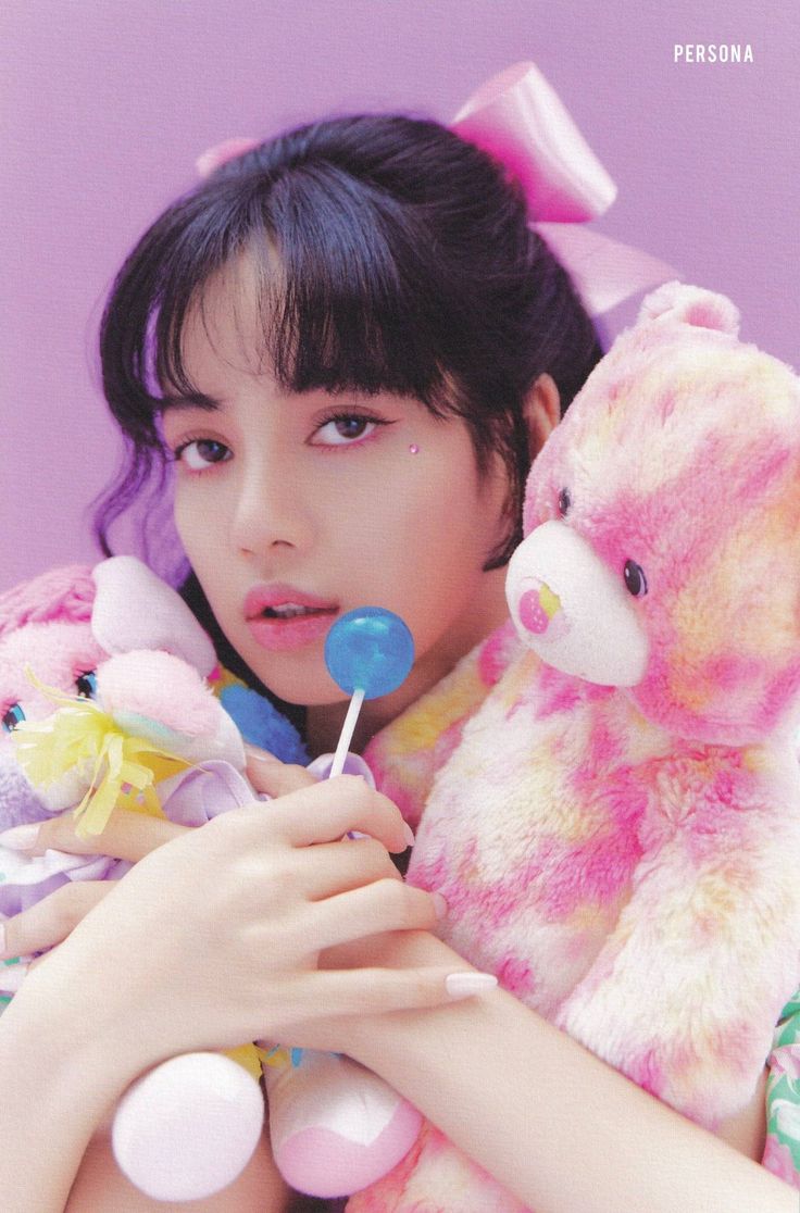 a girl holding two stuffed animals and chewing on a lollipop