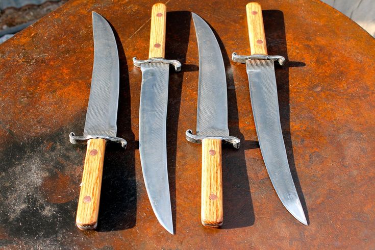 three knives sitting on top of a rusted metal table next to eachother