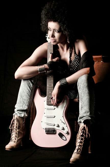 a woman sitting on top of a chair holding a pink guitar