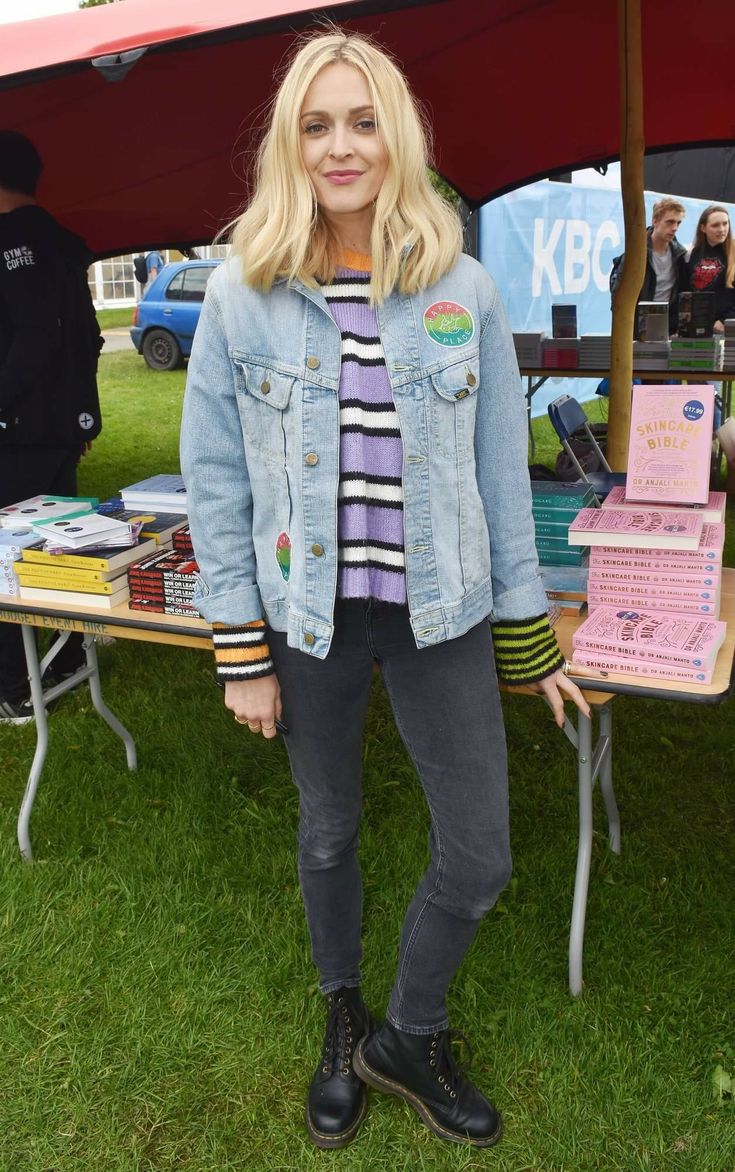 a woman standing in front of a table with books on it at an outdoor event