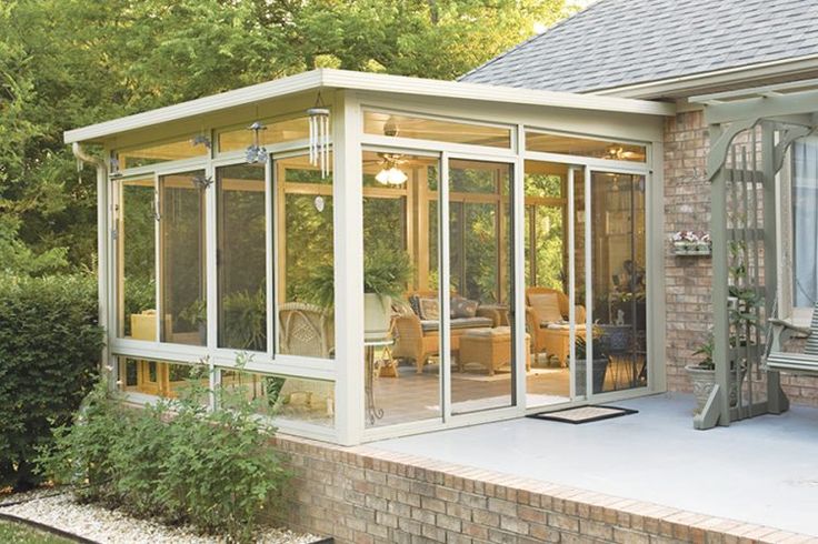 an enclosed patio with glass walls and brick steps leading up to the back of the house