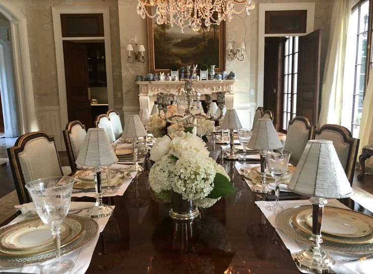 the formal dining room is set with white flowers and place settings for four people to sit at