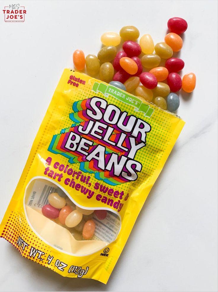 a bag of sour jelly beans sitting on top of a white counter next to some candy