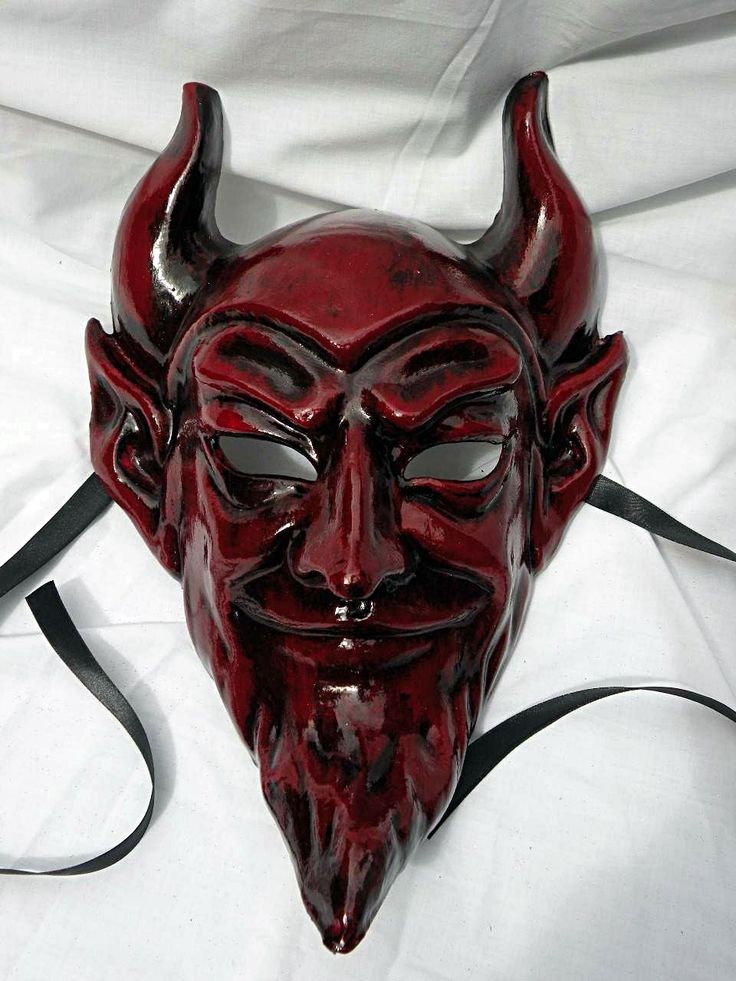 a red mask with horns on it laying on a white sheet