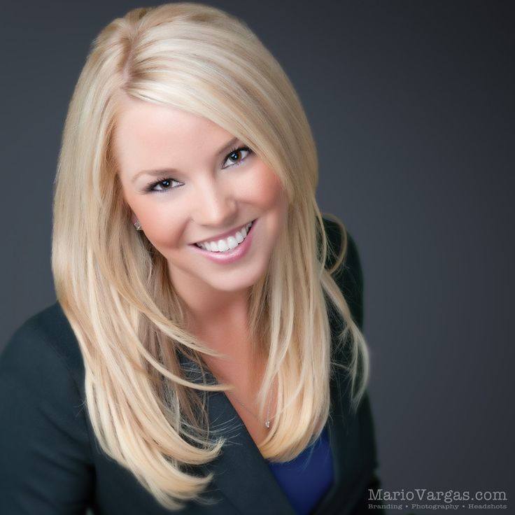 a woman with blonde hair smiling at the camera and wearing a black blazer jacket