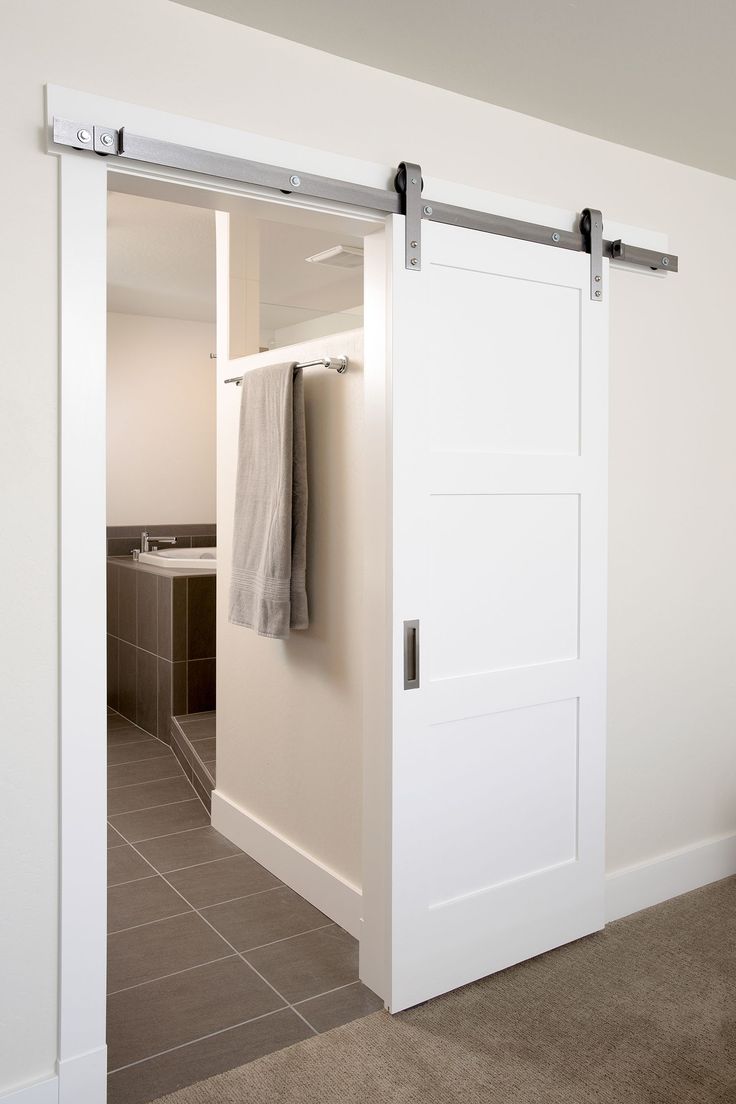 an open sliding door with towels hanging on the handlebars in a white room