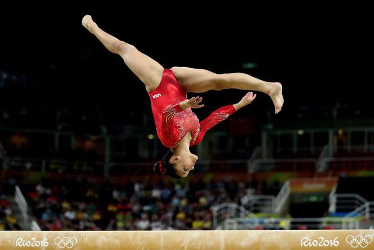 a woman doing a handstand on the balance beam