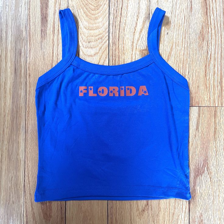 Florida blue and orange tank with star lettering. Perfect for a tailgate or showing spirit! Orange Tops For Women, Casual Tops With Team Name For Tailgating, Blue Sleeveless Collegiate Tops, Collegiate Blue Sleeveless Tops, Orange Casual Tank Top For Sports, Blue Sleeveless Collegiate Style Top, Casual Orange Tank Top For Sports, Blue Graphic Print Sporty Tank Top, Sporty Blue Tank Top With Graphic Print