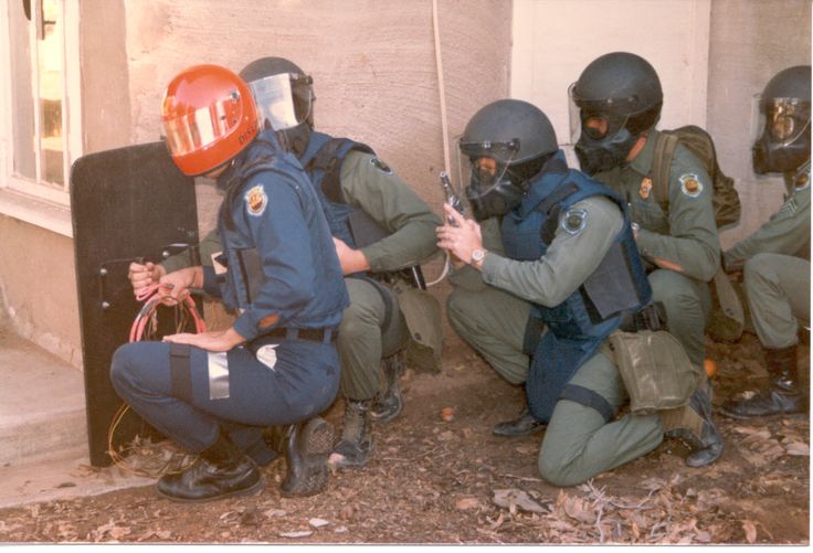 some police officers are kneeling down with their hands on the back of an open door