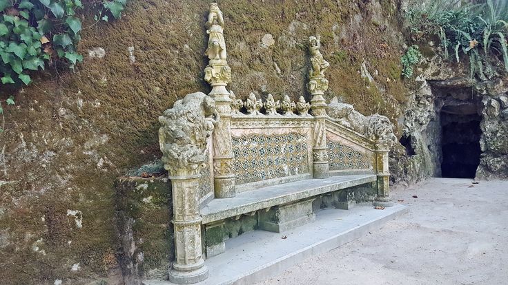 a bench sitting in front of a stone wall with carvings on the back and sides