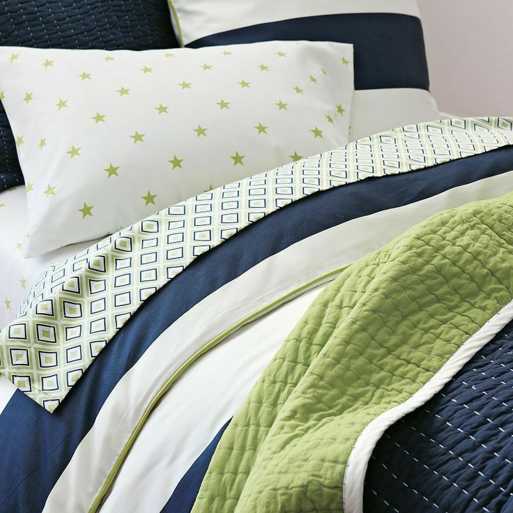 a bed with blue, green and white comforters