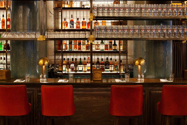 a bar with red chairs and bottles on the shelves