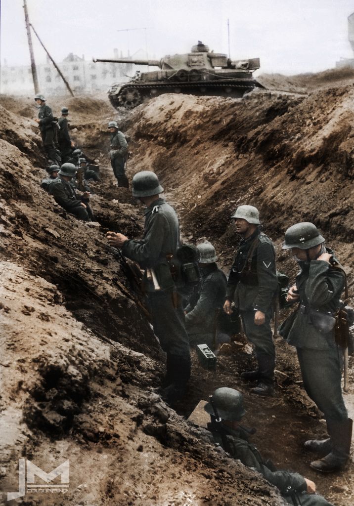 some soldiers are standing on the side of a hill and looking at a tank in the distance